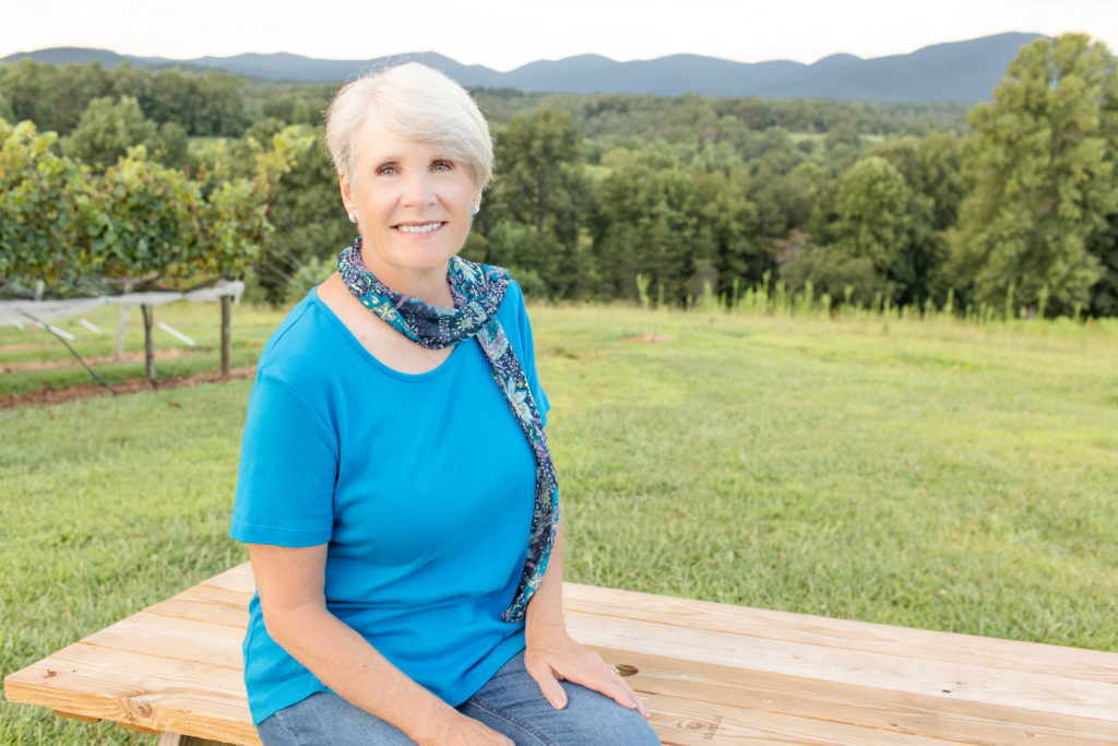 woman on sitting on picnic table with mountains in background