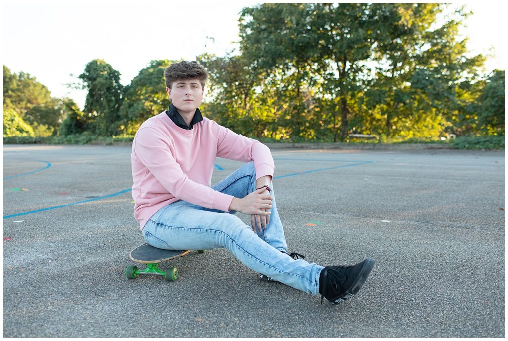 senior male sitting on skateboard